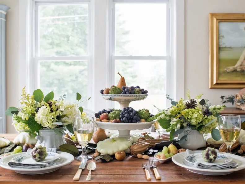 A symmetrical arrangement for the table’s focal point makes a visually strong statement.  In this case, the tall, stacked centerpiece is flanked with two bouquets that were made with the same flowers and produce in vases that are the same size and color.