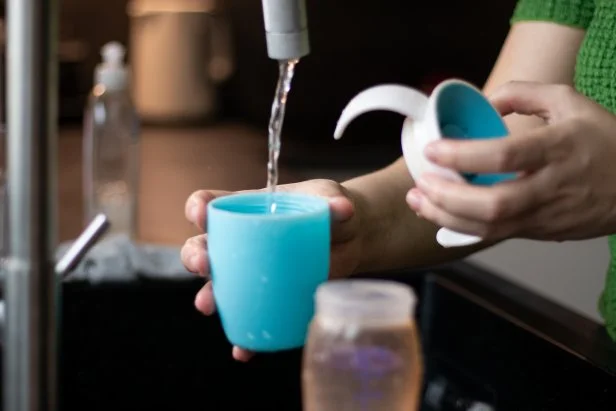 Close up of a woman cleaning a no spill cup for a toddler kid in the kitchen sink