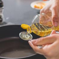 Cook pouring oil into a hot black saucepan