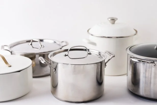 Five stockpots arranged together on a white countertop