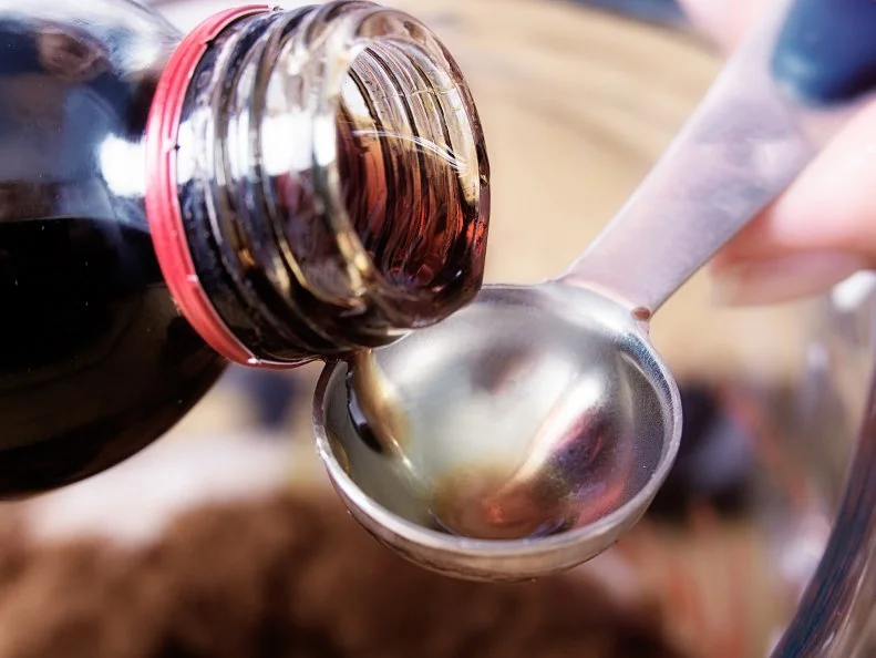 Close-up of medicine being poured onto a teaspoon
