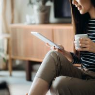 Cropped shot of young Asian woman using digital tablet while working from home in self isolation during the Covid-19 health crisis