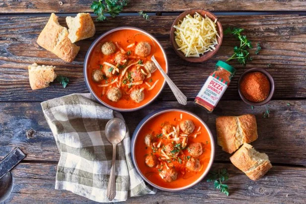 Trader Joe's Pizza Sprinkle Seasoning Blend used in recipe for Soup-zza; in two bowls topped with meatballs, shredded mozzarella and herbs; crusty bread pieces on surface