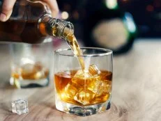 Man pouring whiskey in glasses of whisky drink alcoholic beverage with friends at bar counter in the pub.