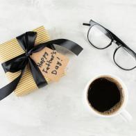 Glasses, coffee cup and craft present box on light background. Happy Father's Day concept. Greeting card. Top view, flat lay
