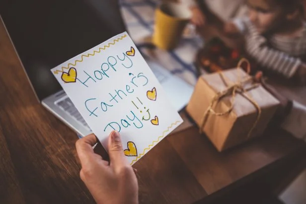 Close-up of father's hands holding handmade card and present from children on father's day