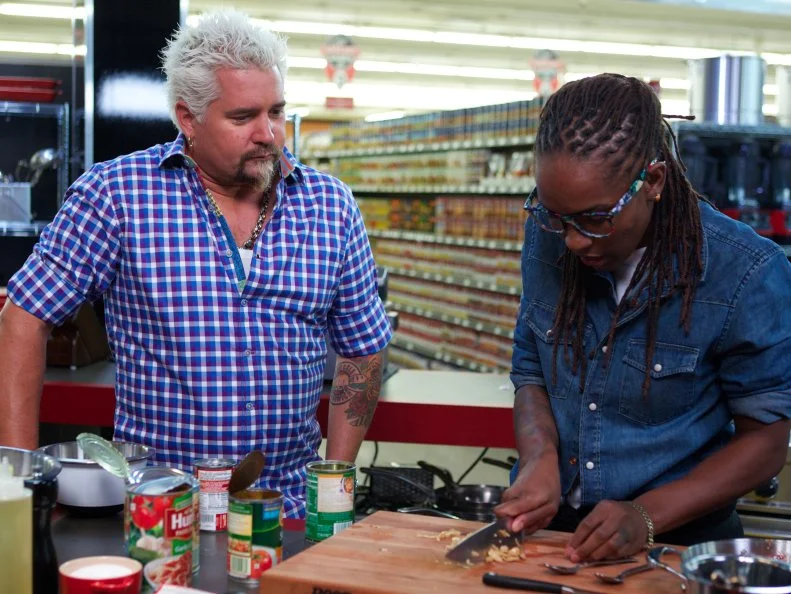 Host Guy Fieri with chef Quiana Jeffries during the cooking part of Game 1, Can Can, Italian Feast, 30 min time limit, as seen on Food Network's Guy's Grocery Games, Season 1.