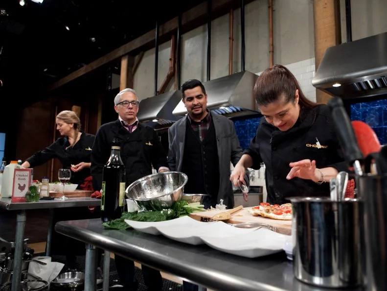 Chopped: After Hours host Aaron Sanchez talks to chef Geoffrey Zakarian while he and chefs Amanda Freitag and Alex Guarnaschelli work on their entrees that must include: deep dish pizza dough, rabbit escabeche, swiss chard and pineapple cheese spread, as seen on Food Network's Chopped: After Hours.
