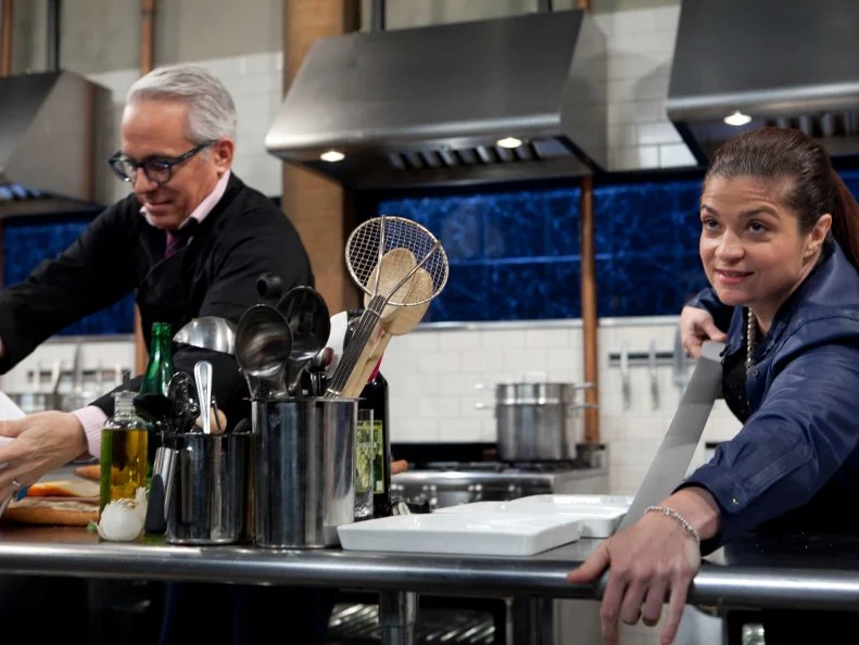 Chopped: After Hours host Alex Guarnaschelli tapes off part of chef Geoffrey Zakarians work station as he is using space he is not allowed to use while working on his entree that must include: tikka masala sauce, Asian long beans, hanger steak and croquettes, as seen on Food Network's Chopped: After Hours.