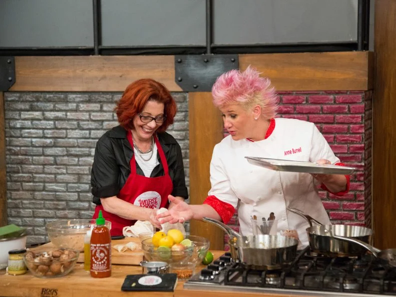 Red Team member Carol Holder races to complete her dish as Red Team Leader Chef Anne Burrell steps in to offer some helpful advice, during the Surprise Party Challenge. She must replicate Red Team Leader Chef Anne Burrell's Chicken & Broccoli Rabe Summer Rolls and Sausage-Stuffed Mushrooms  and infuse it with her candy flavor, lime, as seen on Food Network's Worst Cooks in America, Season 5.