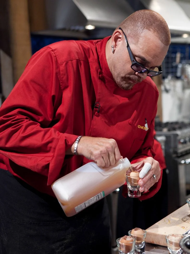 Celebrity Sinbad working on his dessert that must include: cinnamon chips, cheese curls, vanilla cupcakes and apple cider, as seen on Food Networkâ  s Chopped, Season 19.