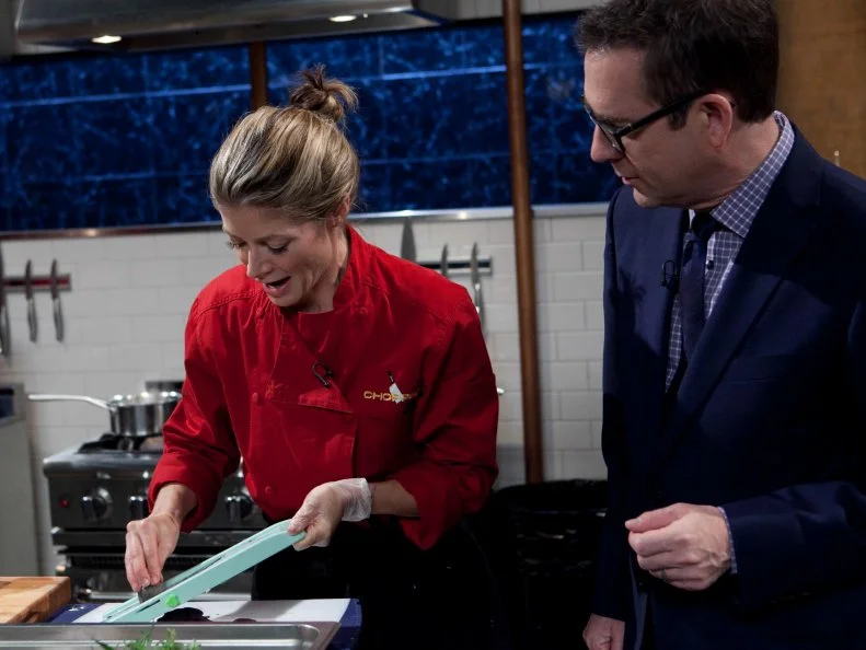 Chopped host Ted Allen checks in on celebrity Gillian Vigman while she works on her entree that must include: beer can chicken, jalapeno poppers, collard greens and truffle honey, as seen on Food Networkâ  s Chopped, Season 19.
