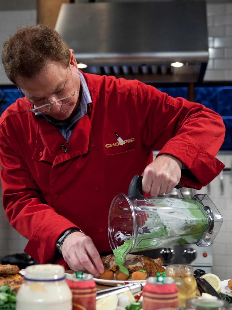 Celebrity Robert Wuhl working on his entree that must include: beer can chicken, jalapeno poppers, collard greens and truffle honey, as seen on Food Networkâ  s Chopped, Season 19.
