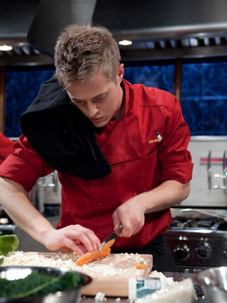 Celebrity Lugas Grabeel working on his appetizer that must include: squid, dinosaur kale, popcorn on the cob and candy blood, as seen on Food Networkâ  s Chopped, Season 19.