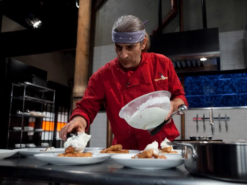 Celebrity Michael Imperioli working on his dessert that must include: blueberry goat cheese, pecans, churros, champagne, as seen on Food Networkâ  s Chopped, Season 19.