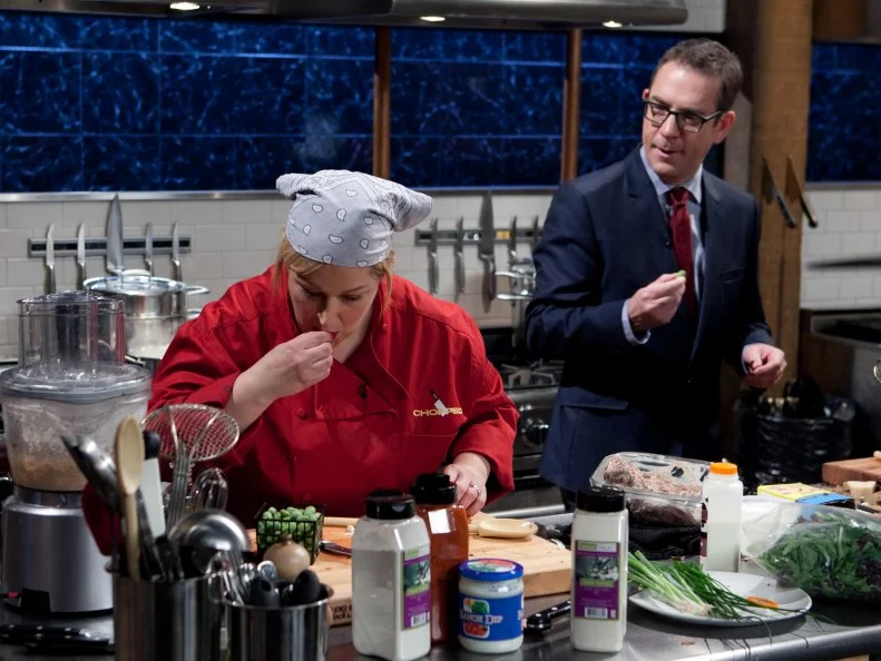 Chopped host Ted Allen checks in on celebrity Carnie Wilson while she works on her entree that must include: buffalo hanger steak, watermelon cucumbers, ranch dip, pizza, as seen on Food Network's Chopped, Season 19.