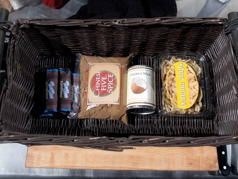 The mystery basket ingredients for the dessert round are: peanut and caramel chocolate bar, chinese five spice, coconut milk, banana chips, as seen on Food Network's Chopped, Season 19.