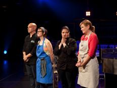 Cooks Christine Verrelli, right, and Stephanie Goldfarb, second from left, pause with Chefs Michael Symon, left, and Alex Guarnaschelli, second from right, as guest judge Chef Bobby Flay (off camera) deliberates the season's winner, as seen on Food Network's America's Best Cook, Season 1.