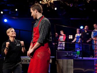 Chef Cat Cora, left, and cook Ben Portman, right, react to comments by guest judge Chef Bobby Flay (off camera), during the judging of the sixth round of competition, as seen on Food Network's America's Best Cook, Season 1.