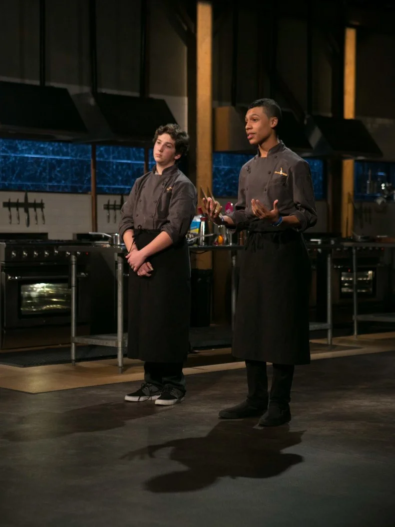 Teen competitors Jason Khaytin (14) and Jay Urena (16) stand before Chopped host Ted Allen and judges: Geoffrey Zakarian, Amanda Freitag and Marc Murphy to defend  their desserts that must have included: gourmet frozen yogurt, white balsamic vinegar, puffed rice cereal bars and dolce de leche, as seen on Food Network's Chopped, Season 21.
