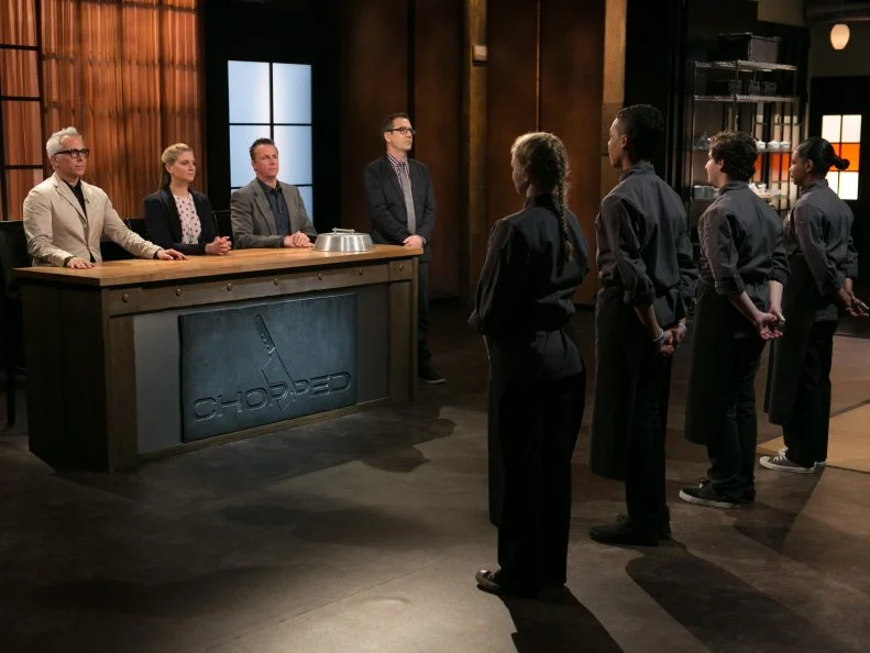 Teen Competitors (L-R) Alexandria Brooks (16), Jason Khaytin (14), Jay Urena (16) and Ashley Dudley (16) stand before Chopped host Ted Allen and judges: Geoffrey Zakarian, Amanda Freitag and Marc Murphy waiting to find out which of them will move on to cook in the next round and who will be chopped, as seen on Food Network's Chopped, Season 21.