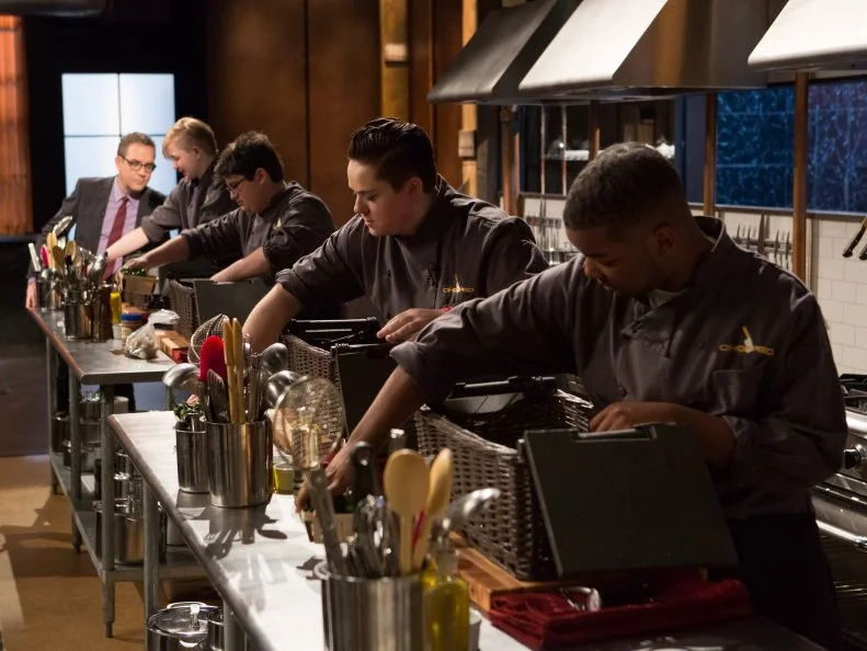 Chopped host Ted Allen tells teen competitors (L-R) Lucy Felong (15), Eyan Goldman (16), Mikayla Lang (13) and Dante Foggy (17 to open their baskets), as seen on Food Network's Chopped, Season 21.