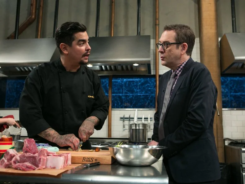 After Hours host Ted Allen checks in on chef Aaron Sanchez while he works on his dish that must include: cherry drink soaked pickles, lamb chops, kale chips and ricotta salata, as seen on Food Network's Chopped After Hours, season 21.
