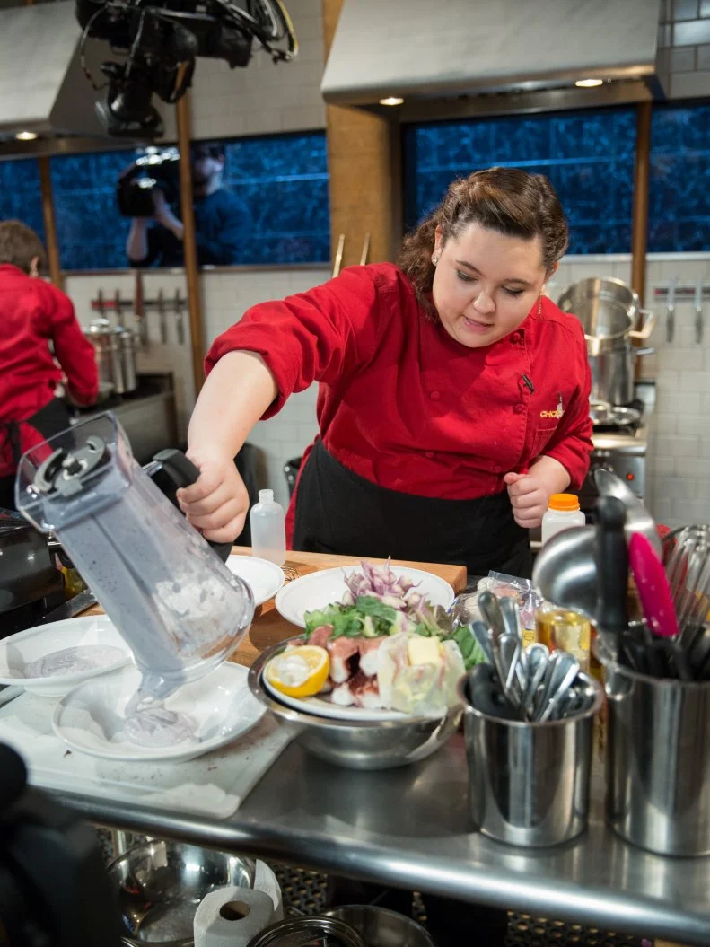 Teen competitor Tommi Rae Fowler cooking during a competition, as seen on Food Networkâ  s Chopped, Season 21.