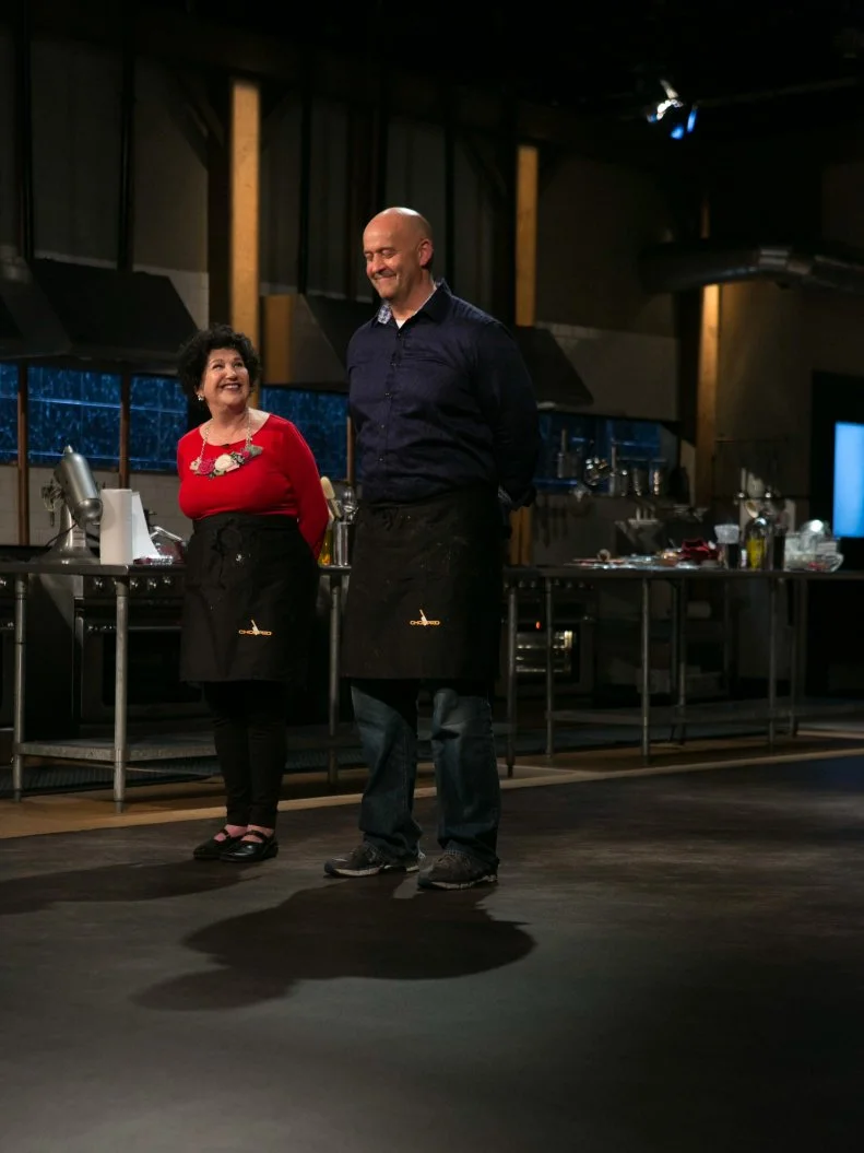 Amateur chefs Elda Bielanski and Keith Young stand before host Ted Allen and judges: Scott Conant, Alex Guarnaschelli and Aaron Sanchez to defend their desserts that must include: cookie spread, creme anglaise, grapefruit and microwave mug cupcakes as they compete for a slot in the Chopped Ultimate Championship competition, the winner of which receives $50,000 and a new car from Buick, as seen on Food Network's Chopped, Season 21.