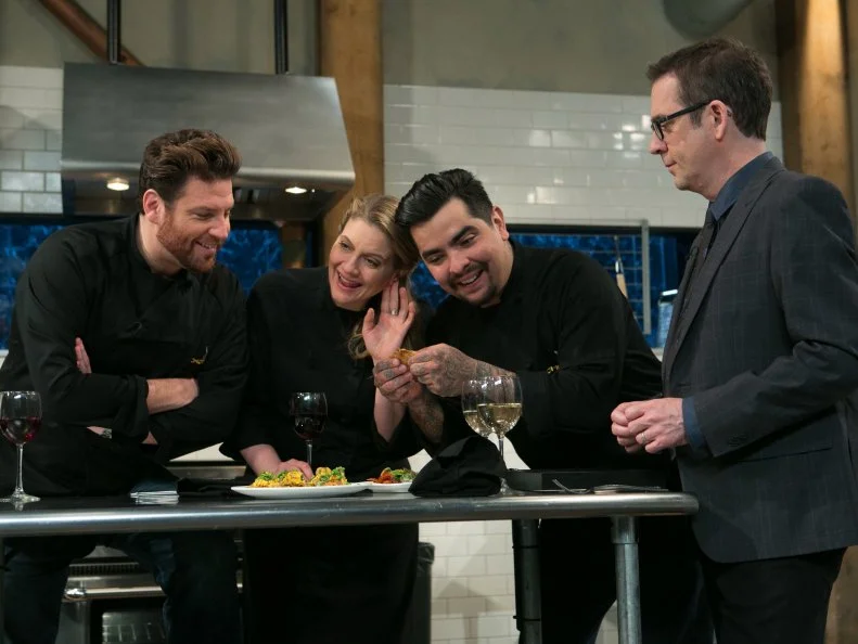Chef Aaron Sanchez wants to show judt how crispy his cripspy pork skin is to Chopped After Hours host Ted Allen and the other chefs while tasting his work with suckling pig, kebab sauces, fiddle head ferns and fresh corn tortillas, as seen on Food Network's Chopped After Hours, Season 21.