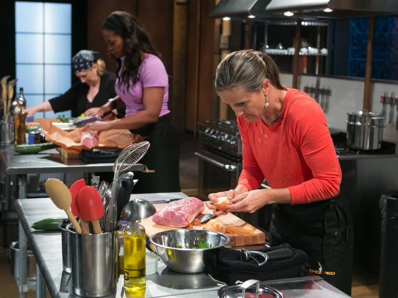 Celebrity chefs (L-R) Carnie Wilson, Laila Ali and Brandi Chastain work on their entrees that must include: pork loin, chocolate body paint, cucumbers and black bean soup as they all compete for a slot in the Chopped Ultimate Championship competition, the winner of which receives $50,000 and a new car from Buick, as seen on Food Network's Chopped, Season 21.