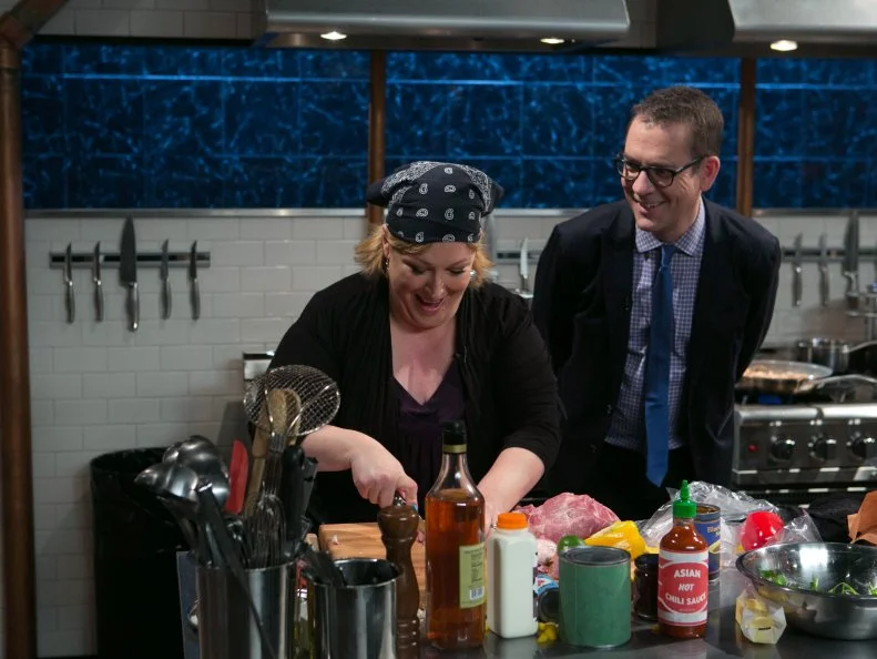 Chopped host Ted Allen checks in on celebrity chef Carnie Wilson as she works on her entree that must include: pork loin, chocolate body paint, cucumbers and black bean soup as she competes for a slot in the Chopped Ultimate Championship competition, the winner of which receives $50,000 and a new car from Buick, as seen on Food Network's Chopped, Season 21.