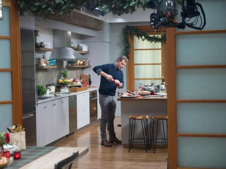 Host Bobby Flay and his guests Alex Guarneschelli, Anne Burrell, Katie Lee, Sunny Anderson, Eddie Jackson, Geoffrey Zacharian, and Scott Conant prepare dinner as seen on Food Network’s Bobby Flay’s Barbecue Addiction, Christmas at Bobby’s Special