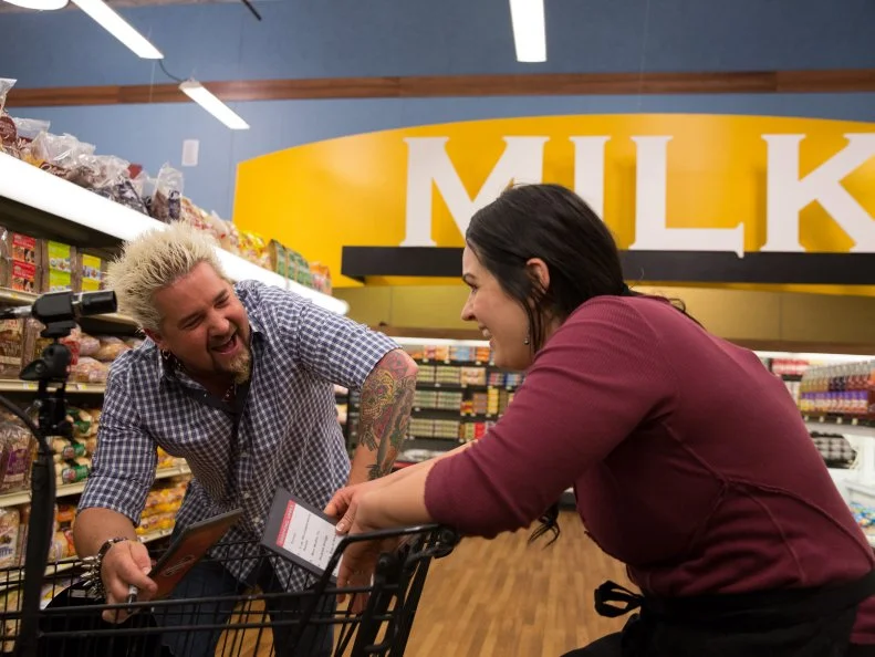 Host Guy Fieri jokes with Chef Veronica Eiken after her winning Shopping Spree, as seen on Food Network's Guy's Grocery Games, Season 7.