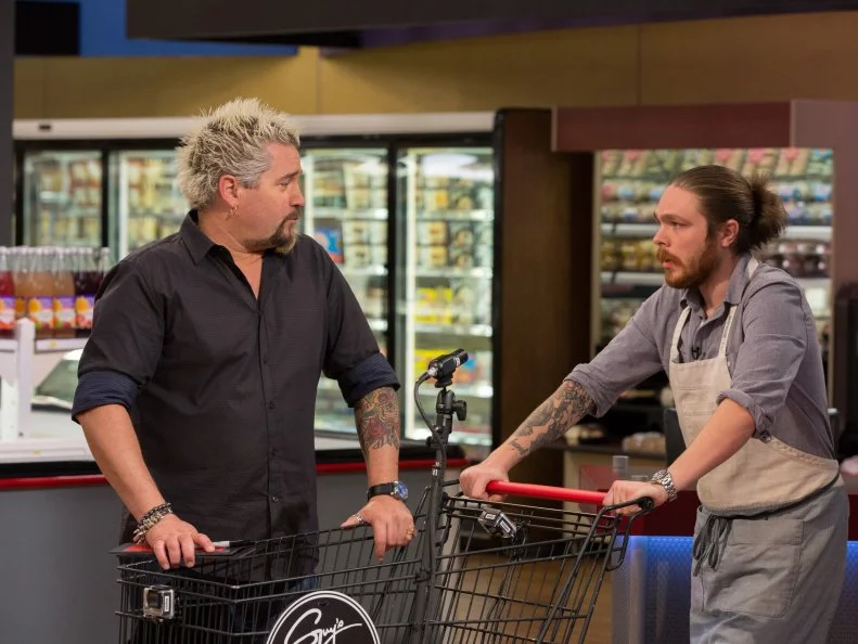 Host Guy Fieri talks with Chef Phillip Franklin Lee before the winning Shopping Spree, as seen on Food Network's Guy's Grocery Games, Season 7.
