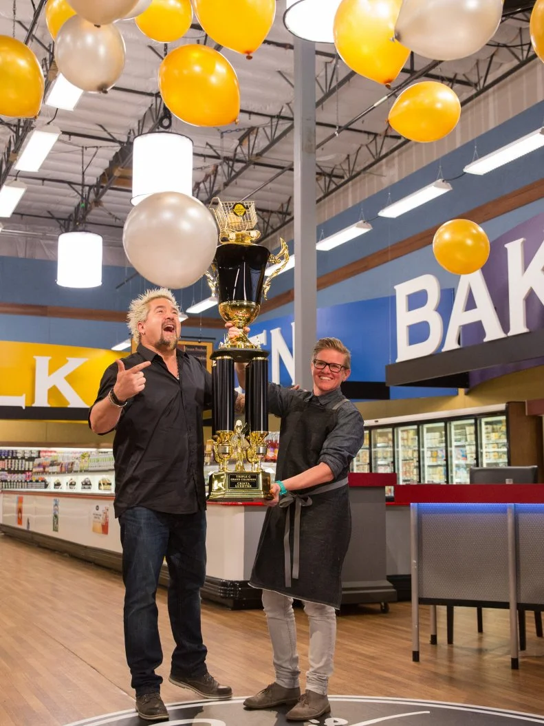 Host Guy Fieri and Chef Crista Luedtke with the Tournament of Champions Trophy, as seen on Food Network's Guy's Grocery Games, Season 7.