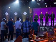 The participant cooks line up during the introduction of the first challenge by mentor chefs Curtis Stone (L), Alex Guarnaschelli, Michael Symon, Bobby Flay and host Ted Allen, as seen on Food Network's All-Star Academy, Season 1.