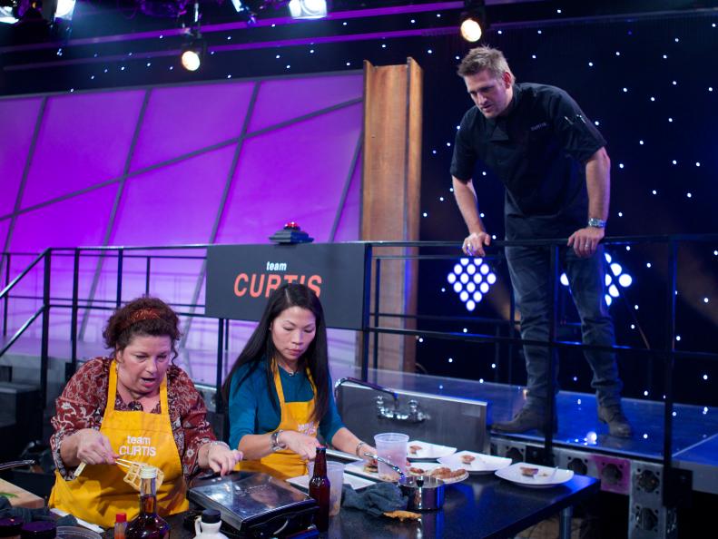 Chef Curtis Stone mentors Sharon Damante (L) and Mimi Turbitt Chang of Team Curtis during the first challenge where each team was given a different assignment. Team Alex was assigned Meat & Potatoes, Team Bobby was assigned Spaghetti & Meatballs, Team Michael was assigned Surf & Turf and Team Curtis was assigned Chicken & Waffles, as seen on Food Network's All-Star Academy, Season 1.
