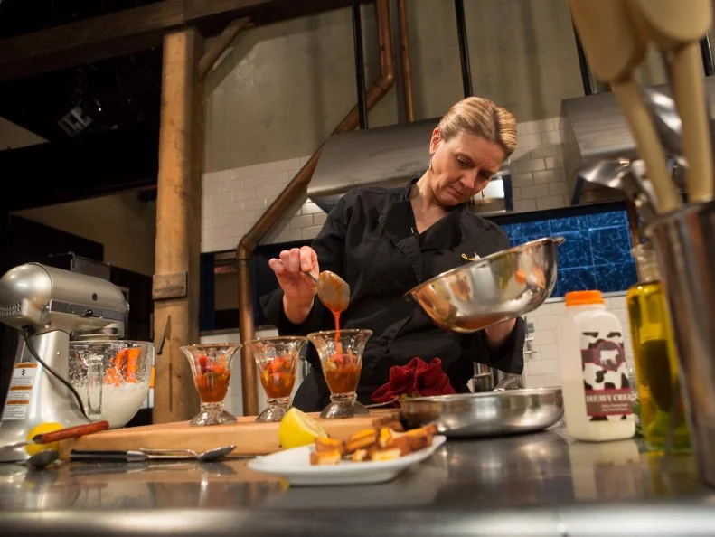 Chef Amanda Freitag working on her dish that must include: April fools day ingredients that are not what they seem. grilled cheese sandwiches = pound cake and frosting, tomato soup = strawberry puree, milk = buttermilk, peas and carrots = jelly beans, as seen on Food Network's chopped After Hours, season 23. as seen on Food Network's Chopped After Hours, Season 23.