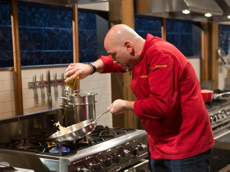 Chef Michael Psilakis works on his entree that must include:  lamb ribs, kumquats, white radicchio and spoon fruit for Chopped All-Stars $75,000 charity competition, as seen on Food Network's Chopped, Season 24.