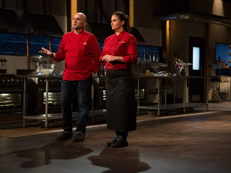 Chefs Antonia Lofaso and Michael Psilakis stand before host Ted Allen and judges: Geoffrey Zakarian, Alex Guarnaschelli and Aaron Sanchez to defend their desserts that must have included: ghee, m'smen, whole walnuts and orange flavored water for Chopped All-Stars $75,000 charity competition, as seen on Food Network's Chopped, Season 24.