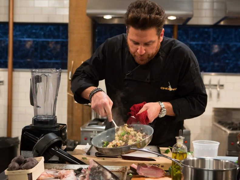 Chef Scott Conant works on his appetizer made from the mystery basket ingredients from episode-24-07 (all star finale) are: fish carcass, calabrian chiles, tasso ham and purple potatoes, as seen on Food Networks Chopped, season 27 webisode