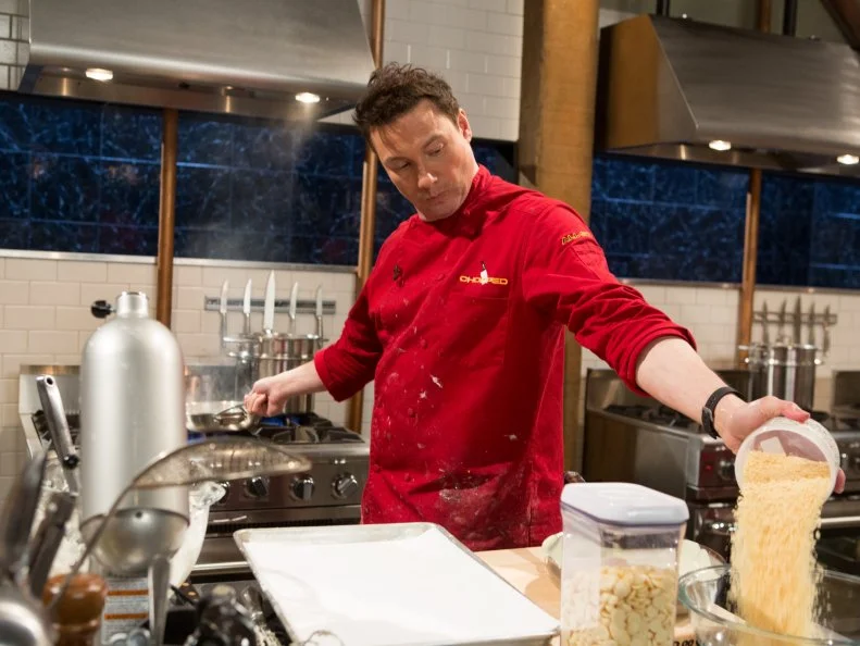 Chef Rocco Dispirito works on his dessert that must include: pistachio cream, dried plums, fish shaped pretzels and carbonated crystals for Chopped All-Stars $75,000 charity competition, as seen on Food Network's Chopped, Season 24.