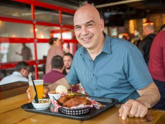 Host Michael Symon poses right before he digs into his meal of hot chicken, black-eyed peas and blackberry cobler , as seen on Food Networkâ  s Burgers, Brew and 'Que, Season 1.