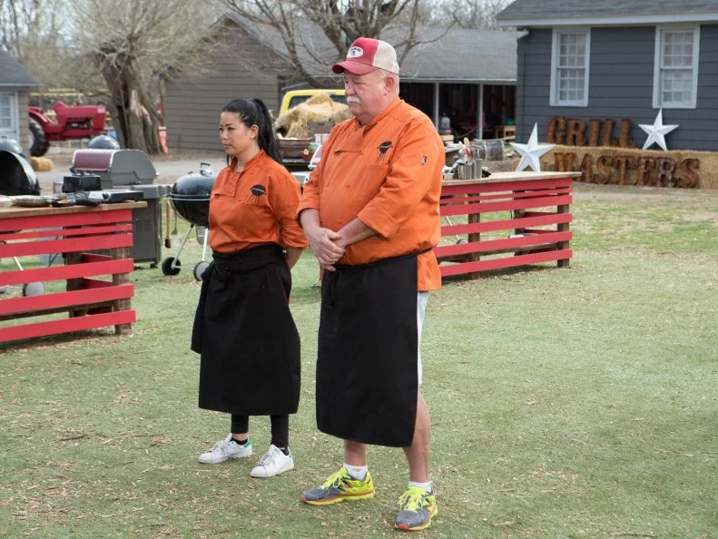 Chefs Mike Davis and Angie Mar stand before Chopped host Ted Allen and judges: Scott Conant, Amy Mills and Chris Santos to defend their desserts that must include: plums, halloumi cheese, poor mans toffee and white bbq sauce, as seen on Food Network's Chopped, Grill Masters Special.