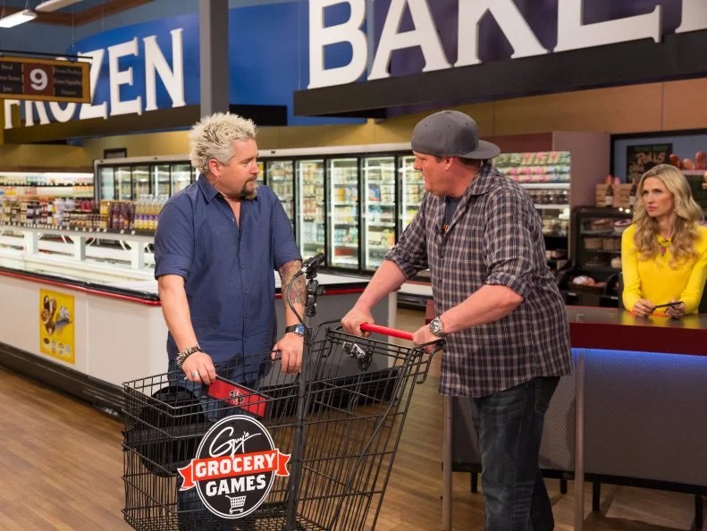 Host Guy Fieri prepares Judge Chef Beau MacMillan for his winning Shopping Spree, as seen on Food Network's Guy's Grocery Games, Season 7.