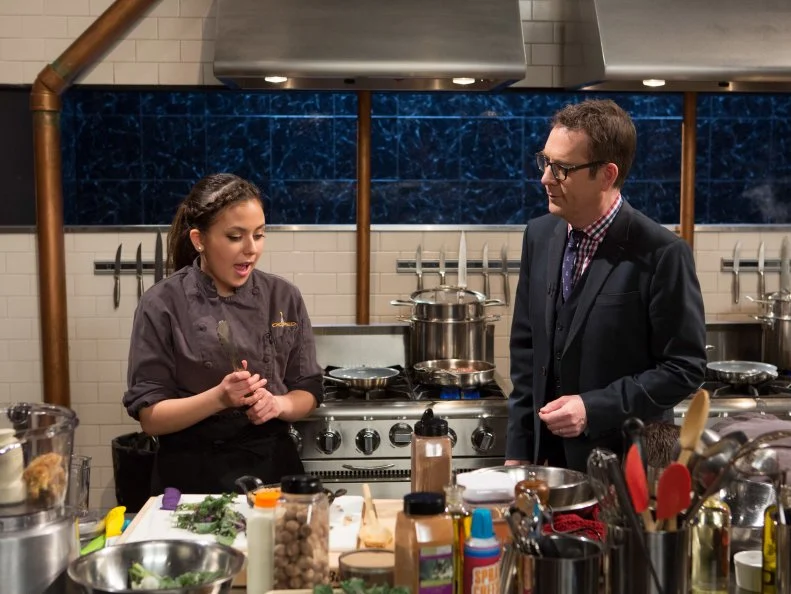 Chopped host Ted Allen checks in on 16 year old Yazmene Kaylani as she works on her entree that must include: hanger steak, lollipop kale, apple crisp and spray cheese for Chopped Teen Week $25,000 tournament, as seen on Food Network's Chopped, Season 25.