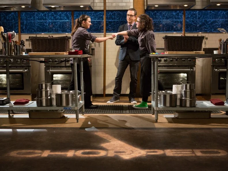 (L-R) Teens Yazmene Kaylani (16) and Anna Mindell (15) face each other in front of Chopped host Ted Allen for Chopped Teen Week $25,000 tournament, as seen on Food Network's Chopped, Season 25.