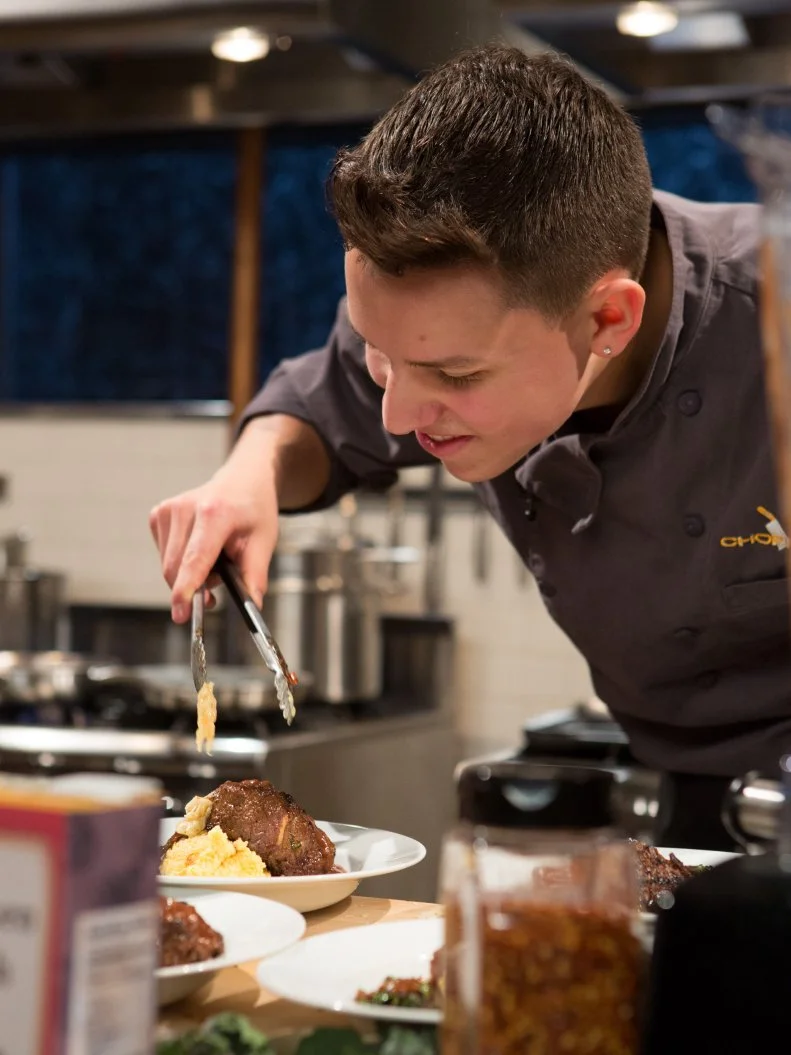 17 year old Theo Vicioso works on his entree that must include: hanger steak, lollipop kale, apple crisp and spray cheese for Chopped Teen Week $25,000 tournament, as seen on Food Network's Chopped, Season 25.