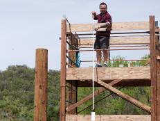 Host Alton Brown watches Judge Jet Tila try out the Round 1 sabotage element, Lookout Tower Prep & Cook, as seen on Food Network's Cutthroat Kitchen, Camp Cutthroat Special.